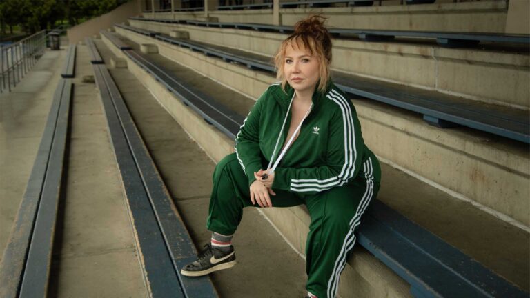 Woman with wearing a green track suit sitting on bleachers